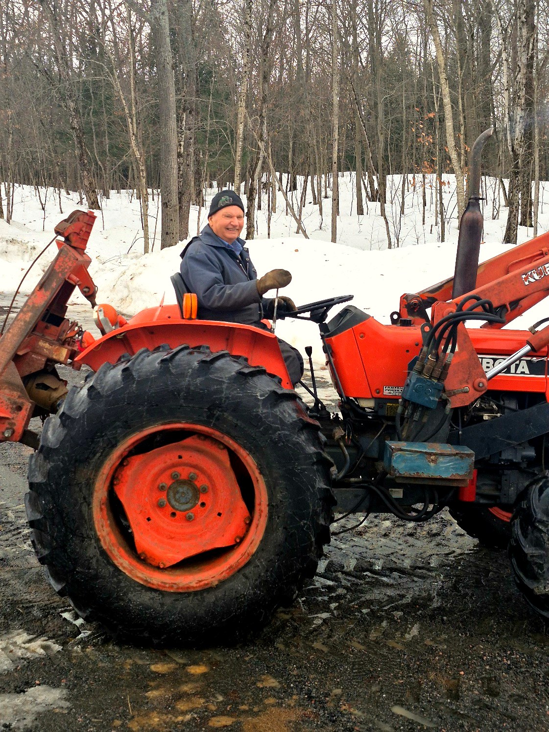 Keith seated on an orange tractor in the snow